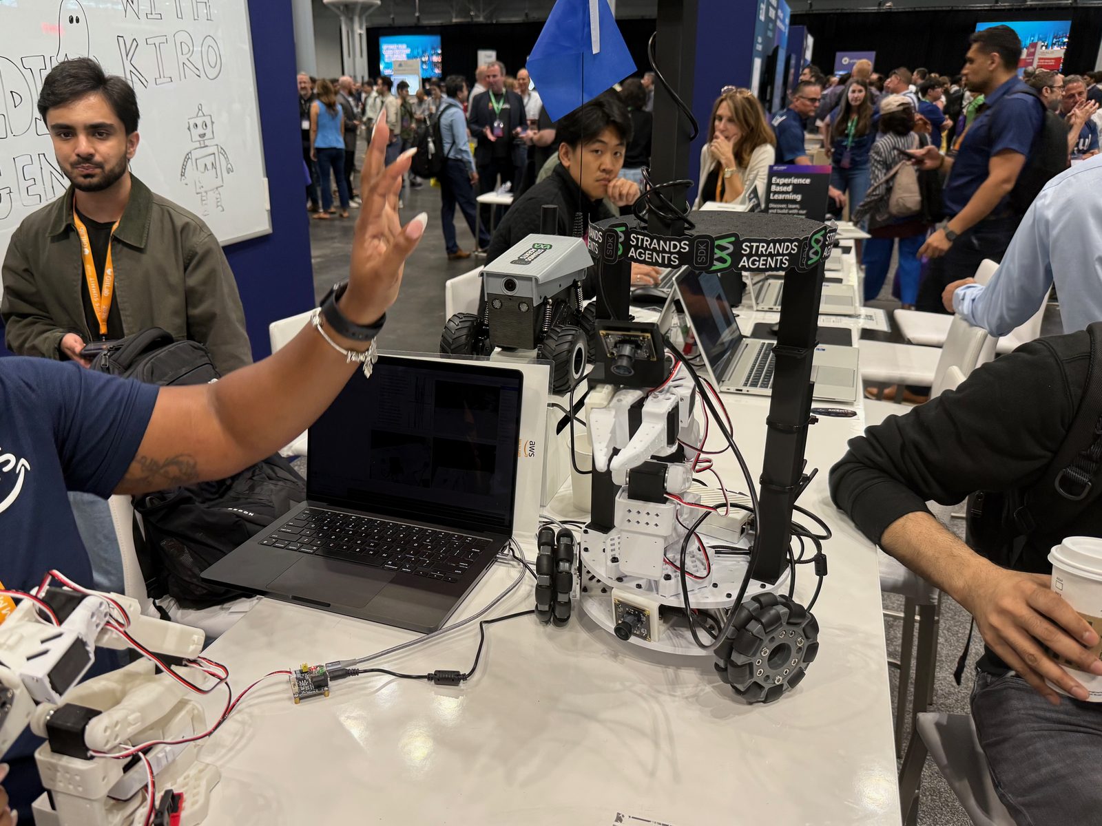 Robots on a demo table under Strands Agents signage, with builders gathered around laptops